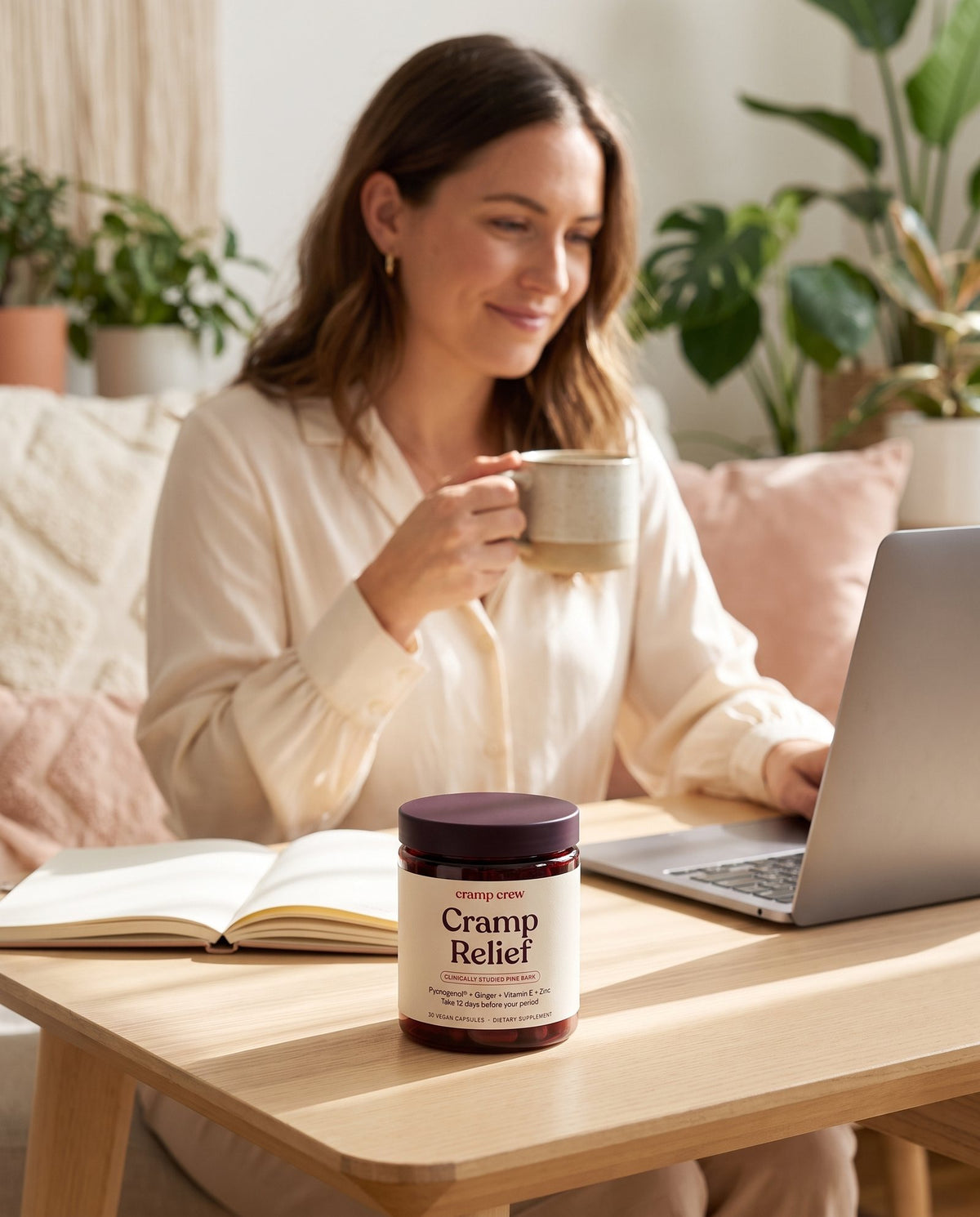 Relaxed woman working at her desk with a jar of Cramp Relief next to her laptop
